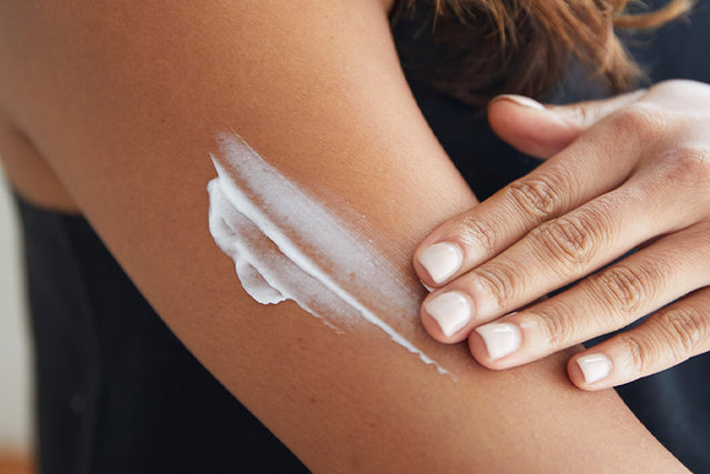 A person applying moisturizer to their arm