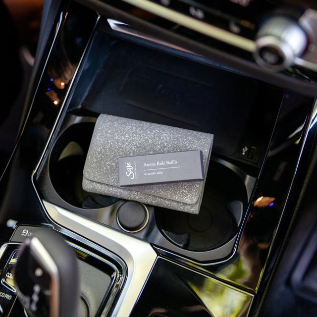 Aroma Ride Refills in a car atop the cup holders in the front seat