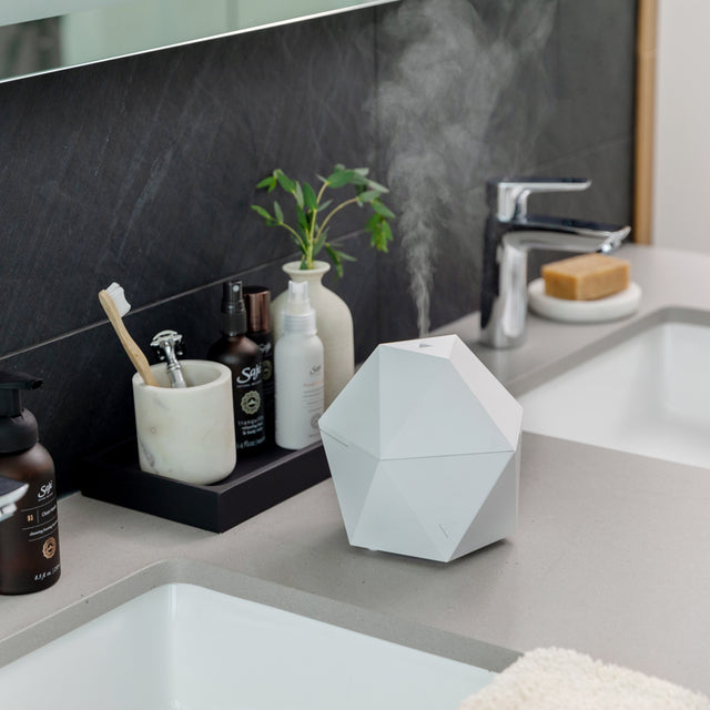White Aroma Be Free diffuser diffusing on bathroom counter.