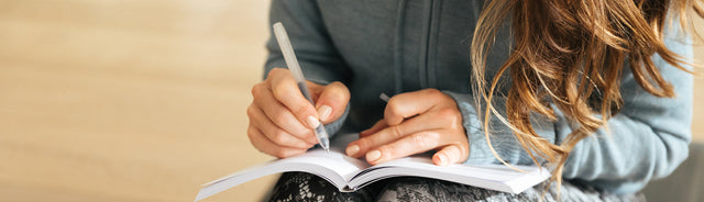 Woman in a blue sweater writing in a journal