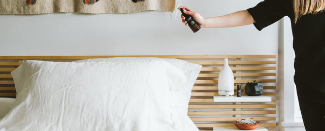 A person spraying sweet sheets onto bed