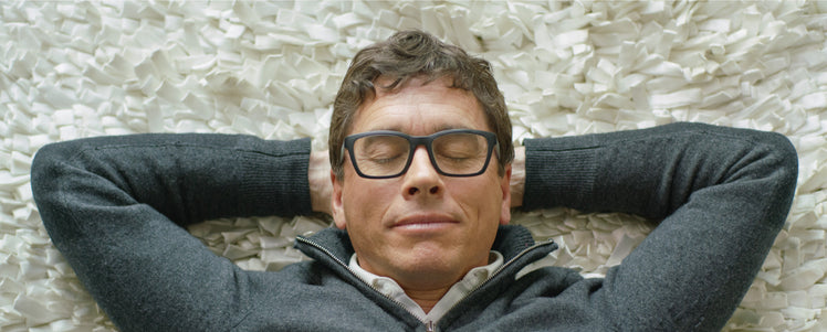 Jean-Pierre lying down with his hands behind his head and eyes closed