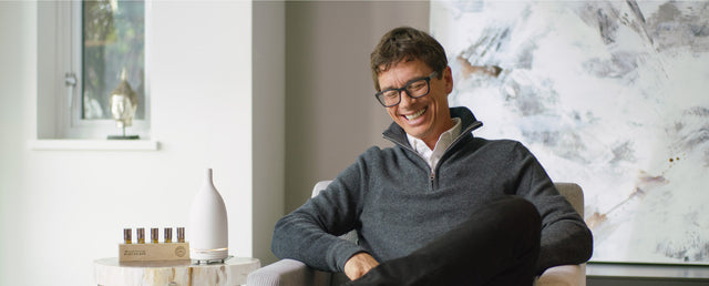 Jean-Pierre sitting on a chair placed with aroma om diffuser and diffuser blends