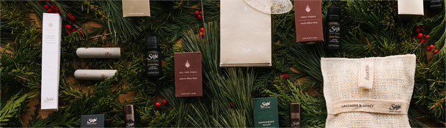 Saje Holiday Collection placed on holiday greenery