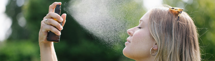 A person spraying face mist on their face