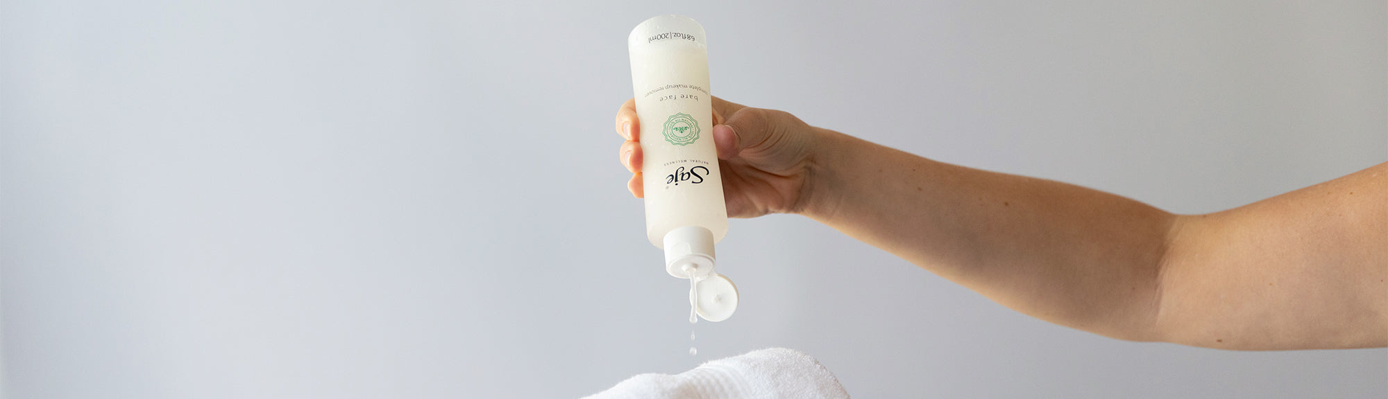 Saje Bare Face makeup remover being dispensed onto a white face towel