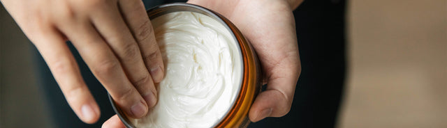 A person's hand scooping out Saje body butter