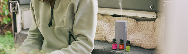 A person sitting beside Saje cordless diffuser and summer diffuser blend collection
