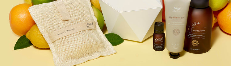 Saje Liquid Sunshine collection and white diffuser with fresh citrus fruit in the background