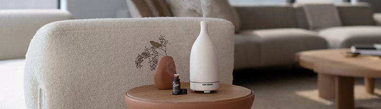 Aroma Om diffuser placed on a side table next to a Saje diffuser blend