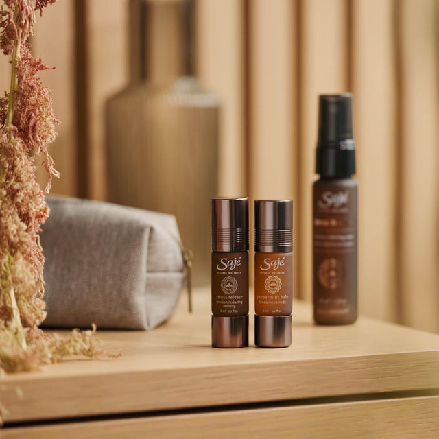 Stress release roll-on, peppermint halo roll-on and stress release mist next to grey pouch sitting on a wooden side table
