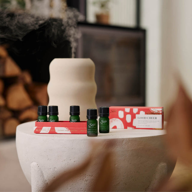 Good Cheer Diffuser Blend Collection sitting on a cement coffee table next to an Aroma Wave Diffuser