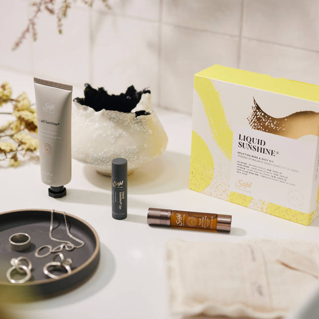 Liquid sunshine kit with products out of packaging sitting on a white counter next to a grey tray with silver jewelry