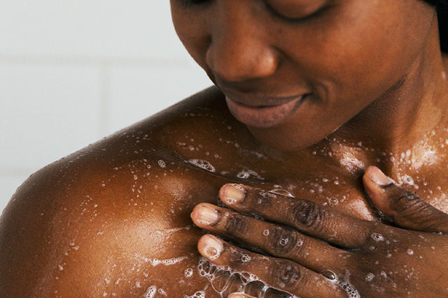 A person lathering in the shower with Saje body wash