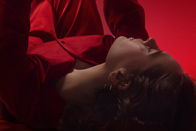 A relaxed person lies down against a crimson red background that fades into black.