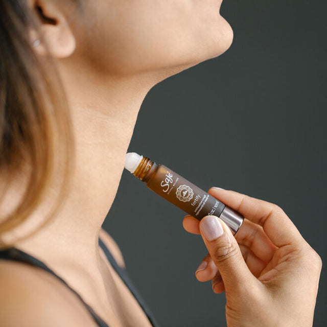 A woman applying Fortify roll-on to her neck in a side profile