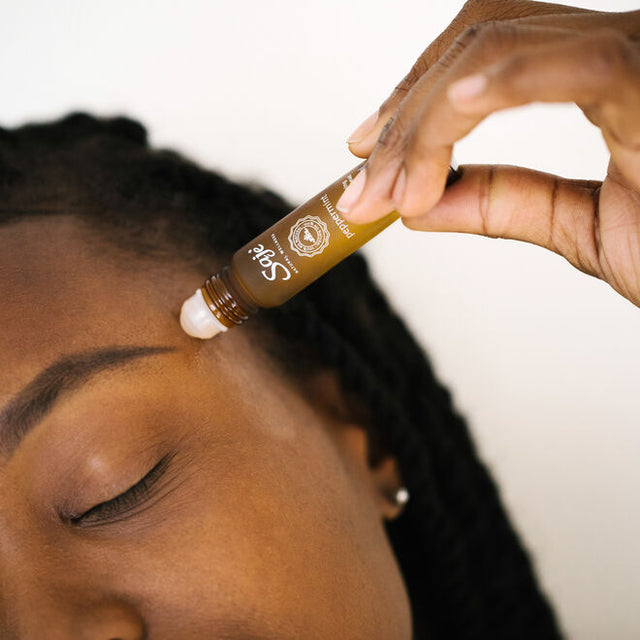 Person rolling Saje Wellness Peppermint Halo on temples