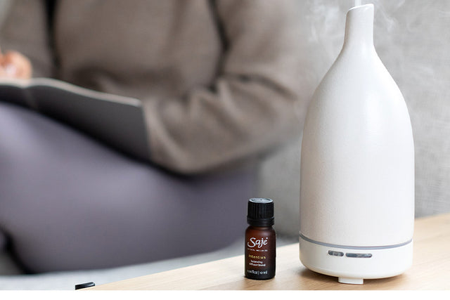 dropping essential oil from a diffuser blend in a diffuser