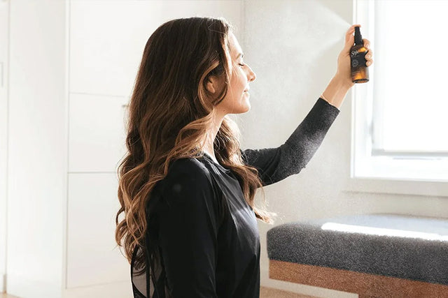 Person spraying Stress Release mist in front of a bright window