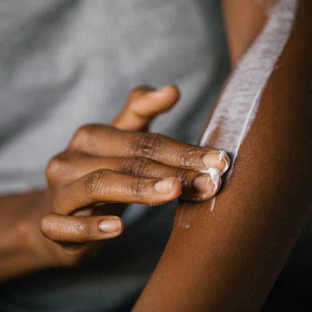 A hand applying body butter to the opposite forearm