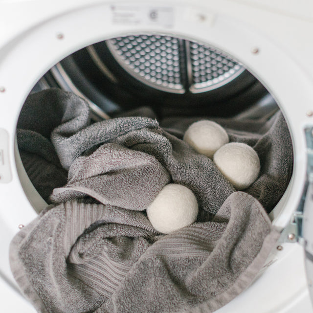 3 wool dryer balls placed inside a dry full of towels 