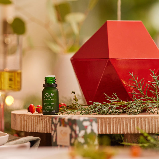 Red Aroma Be Free diffuser on table with greenery.