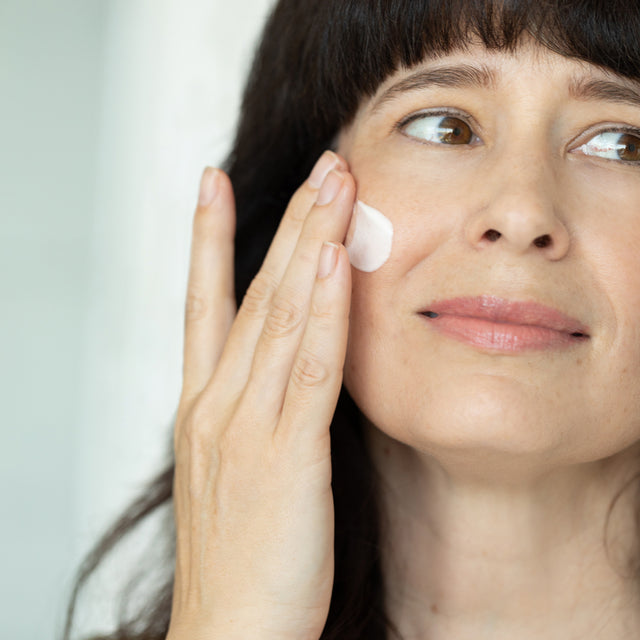 A woman applying true dew moisturizer onto their face
