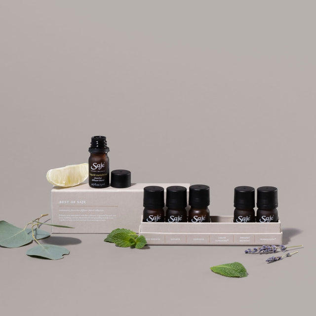 Best of Saje Diffuser Blend Collection stylized with mint, lavender, lemon and eucalyptus plants on a grey background