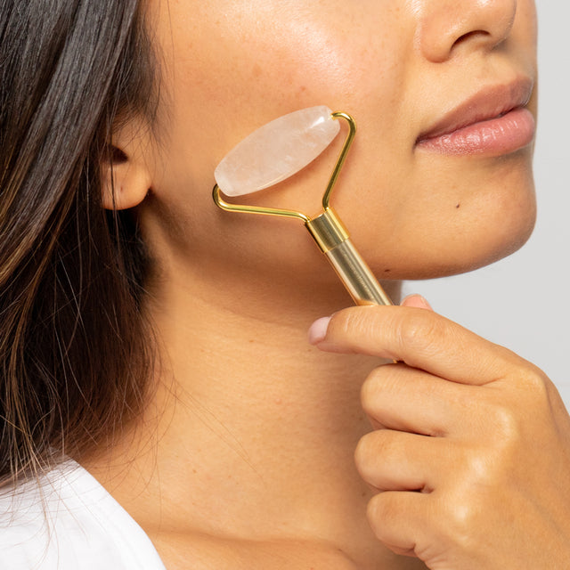 Woman using the Clear Quartz facial roller on her cheek