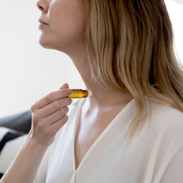 A woman applying a roll-on to her neck 
