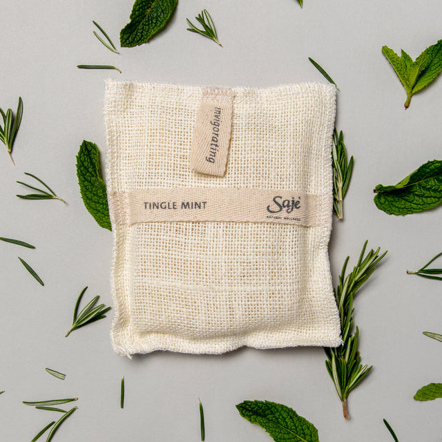 Tingle Mint Jute & Joy Wash Pad surrounding by rosemary and mint leaves